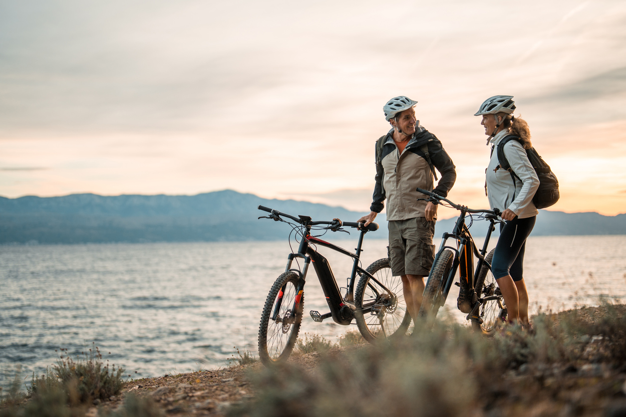 Active Senior Couple with Electric Bikes at Sea at Dawn