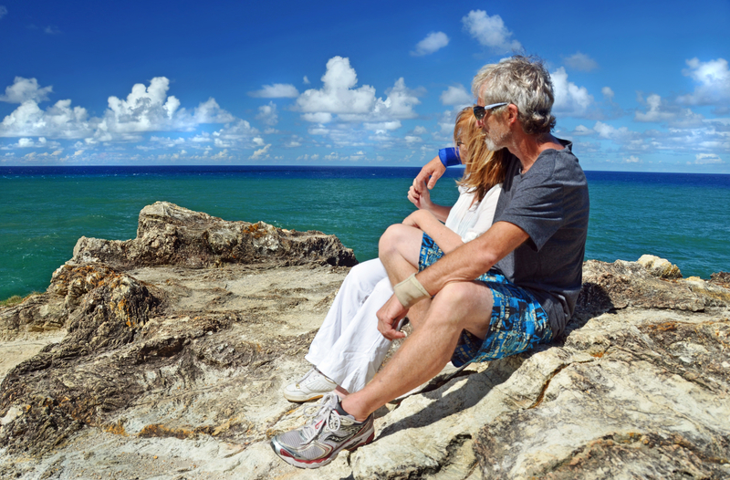 healthy-senior-couple-resting-after-hiking-to-cliff-top-tropical-island-960405869825